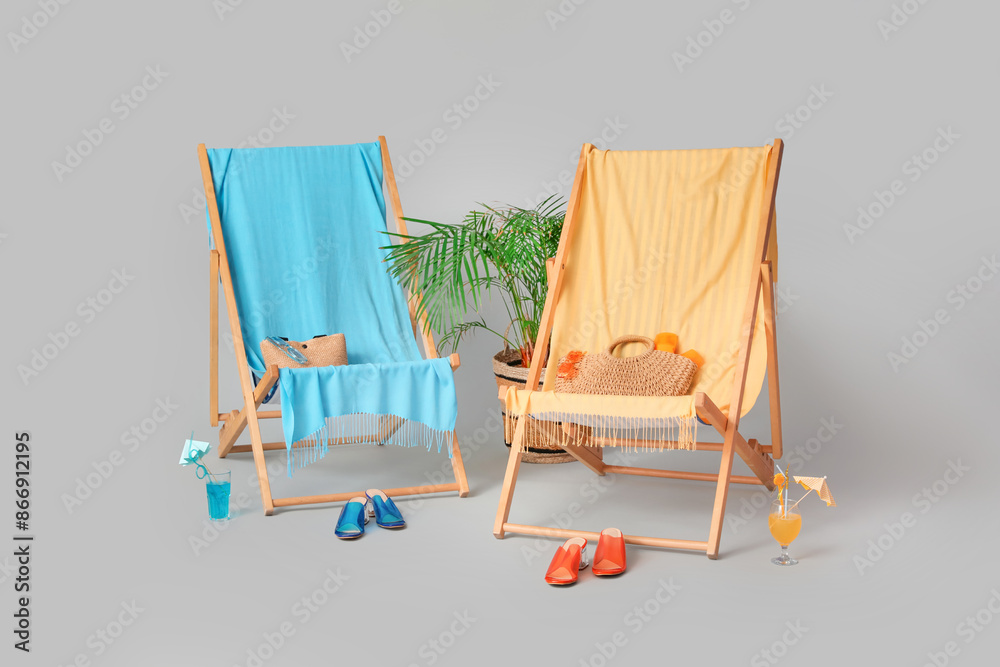 Deckchairs, beach accessories and glasses of cocktail grey background
