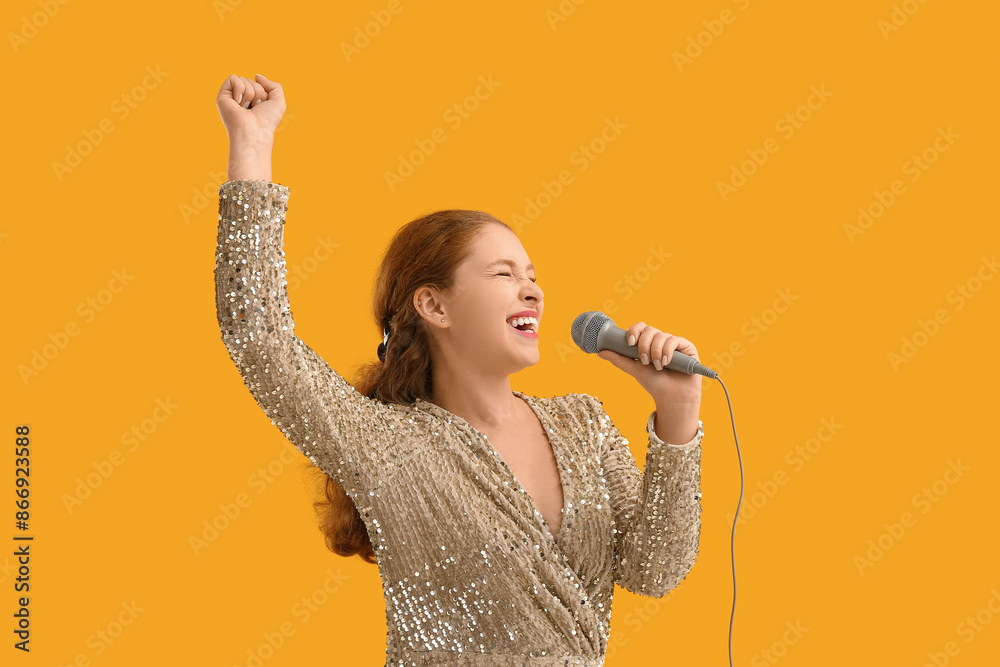 Beautiful young woman singing with microphone on yellow background