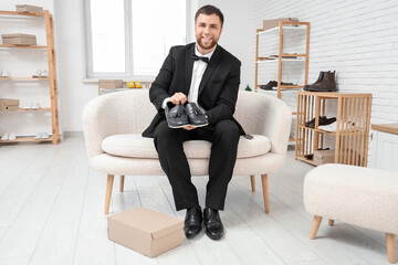 Wall Mural - Happy young man with pair of new shoes in boutique