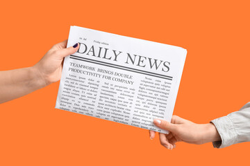 Wall Mural - Female hands with newspaper on orange background