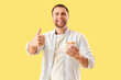 © Pixel-Shot - Handsome young man with tasty doner kebab showing thumb-up gesture on yellow background
