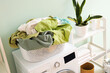 © Pixel-Shot - Full laundry basket on washing machine in room