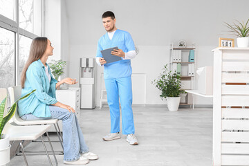 Wall Mural - Male receptionist with waiting patient in clinic