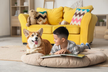 Wall Mural - Little happy Asian boy reading book with cute Corgi dog at home