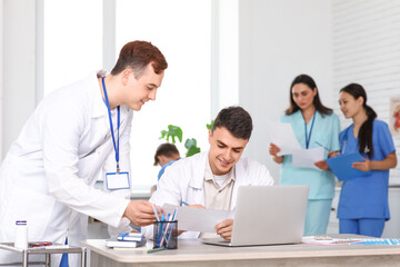 Wall Mural - Male doctors working at table in clinic