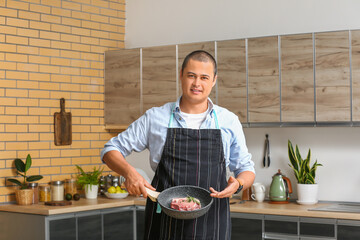 Canvas Print - Young man frying meat in kitchen