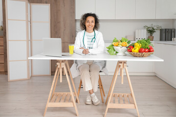 Poster - Mature female nutritionist sitting at table in kitchen