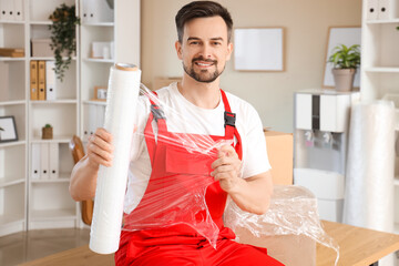 Poster - Male worker with roll of stretch film in office