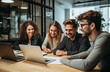 © Minimal Blue - A diverse group of young professionals working together on laptops in a modern office. They are smiling and engaged, reflecting teamwork and collaboration