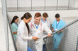 © Pixel-Shot - Group of young doctors with clipboard on stairs in clinic