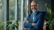 © Achmad Khoeron - Happy middle aged business man ceo standing in office arms crossed. Smiling mature confident professional executive manager, proud lawyer, businessman leader wearing blue suit