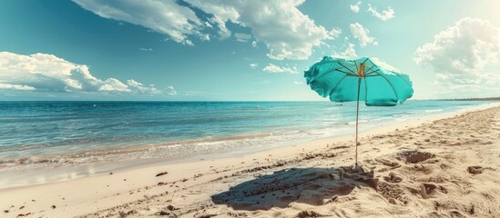 Wall Mural - Deserted beach with an open turquoise beach umbrella on a serene summer morning, perfect for a relaxing vacation