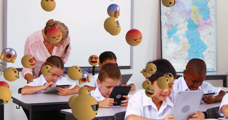 Poster - Image of emoticons floating over diverse female teacher helping students with digital tablet