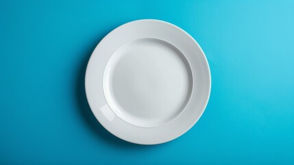 Poster - White ceramic plate on blue background, studio shot. Minimalist kitchenware concept