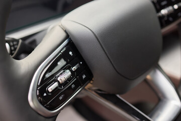 Wall Mural - Closeup of a modern car steering wheel with control buttons for technology and convenience