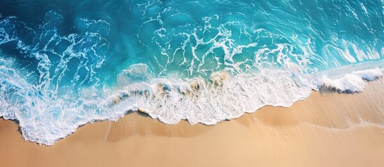 Wall Mural - Peaceful beach scene captured from above with calming waves, stunning blue ocean, and sunlit coastline. Ideal banner for summer vacation getaways.