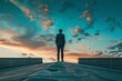 © ylivdesign - Businessman is standing on a rooftop at sunset, contemplating the future