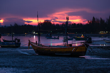 Fishing Wood boat on peaceful calm relaxing on a Beautiful evening landscape with orange sky reflecting on the seawater at sunset