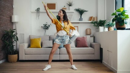 Wall Mural - Video of funny motivated woman dancing and listening to music while sweeping the house