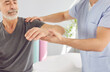 © Studio Romantic - A rehabilitation therapist supports the hand of an elderly man in a medical center. Physiotherapy and rehabilitation concept. A specialist helps a patient restore function after an injury