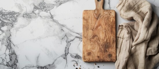 Wall Mural - Top view of a wooden cutting board with a linen napkin on a marble table, with space for text