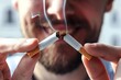 © Yuliia - Close-up of a beautiful man with a well-groomed beard breaking a cigarette, with a smile on his face, in a powerful act of prevention against addiction and cancer.
