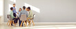 © Studio Romantic - Business coach and team mentor meeting with group of people. Smiling man talking to happy young diverse men and women sitting in circle in modern office with gray copy space wall. Banner background