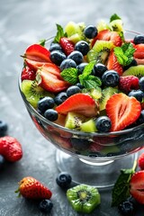 Wall Mural - Fresh fruit salad with strawberries, blueberries, and kiwi garnished with mint leaves