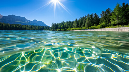 crystal clear water of a mountain lake reflecting green pines and blue sky under bright sun