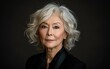 © imagineRbc - A portrait of a woman with grey, curly hair, and dark eyes. She is wearing a black blouse against a dark background