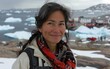 © imagineRbc - A woman with gray hair smiles, wearing a red scarf. The background features a Greenlandic town and icebergs in the water