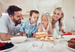 © peopleimages.com - Happy, family and birthday in home with cake for love, celebration and together for care. Parents, children and party or sweets in living room for weekend and candy in kitchen for nutrition or eating