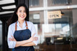 © NAMPIX - Happy Asian woman barista working, Successful small business owner standing with crossed arms looking at camera in restaurant