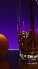 Poster - Beautiful drink is poured into transparent glass. Stock clip. Bright drink is poured into glass on background of ingredients. Fruit around glass with drink on isolated background