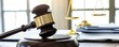 © Answertalker - Closeup of a wooden gavel resting on a soundboard with a scale of justice in the background.