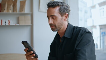 Handsome guy chatting cellphone social networks drinking coffee in cafe close up