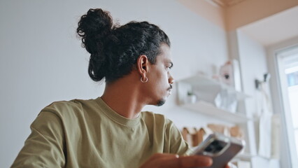 Serious hipster looking smartphone screen sitting modern coffee house close up.