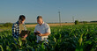 © StockMediaSeller - Two farmers working in a field, using a laptop and a tablet. Technology in agriculture