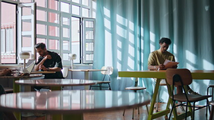 Freelancers sitting cafe coworking place under soft sunlight. Visitors relaxing 