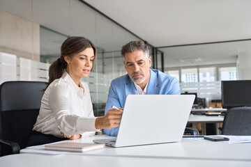 Two busy professional executive team business people working together on business finances analysis looking at computer at office meeting. Professional manager consulting corporate client using laptop