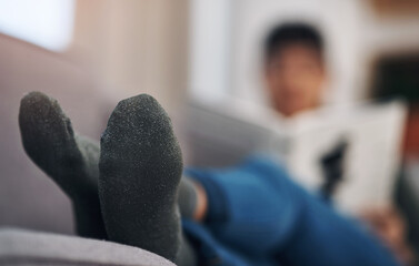 Poster - Home, relax and feet of person on sofa for resting, calm and comfortable in living room. Apartment, weekend and closeup of woman on couch reading book for peace, socks and chilling in house to unwind