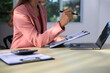 © Worapon - Image of a young Asian female company employee smiling and holding a digital tablet standing on a white background.