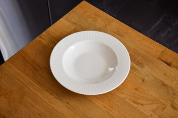 Ceramic white flat plate for food on wooden table top view