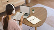 © Pichsakul - Female entrepreneur in headphone to listening music and reading book to relax after working at home
