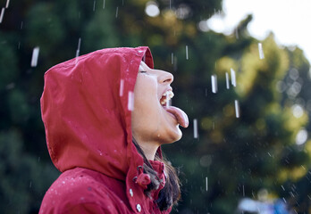 Wall Mural - Feel, rain and woman with raincoat, carefree and tongue in weather of Seattle, travel and explore in vacation. Park, girl and drinking of water, outdoor and happy in winter, holiday and Washington