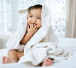 © KayJoint/peopleimages.com - Baby, smile and towel on bed for hygiene with bath time, child skincare and wellness for growth in home. Infant girl, happy and dry after washing for morning cleaning, development and health in house