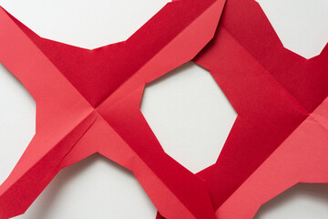 Sticker - folded and cut red paper shapes (stars) with jaunty edges on plain paper