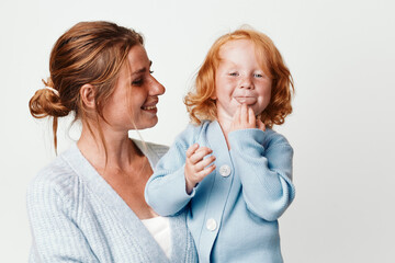 Wall Mural - Mother and child smiling in front of white background, family love and happiness, parenthood and joyful moments