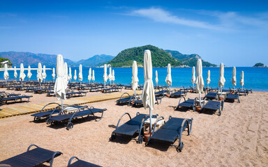 Icmeler Beach in Marmaris, Turkey with rows of folded white parasols and sun loungers on sandy shore, ready for tourists to enjoy calm blue waters. Welcome to Icmeler, Turkey concept image