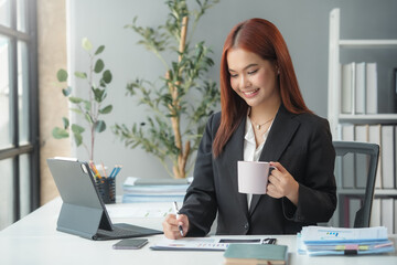 Wall Mural - Businesswoman smiling and working in office with coffee